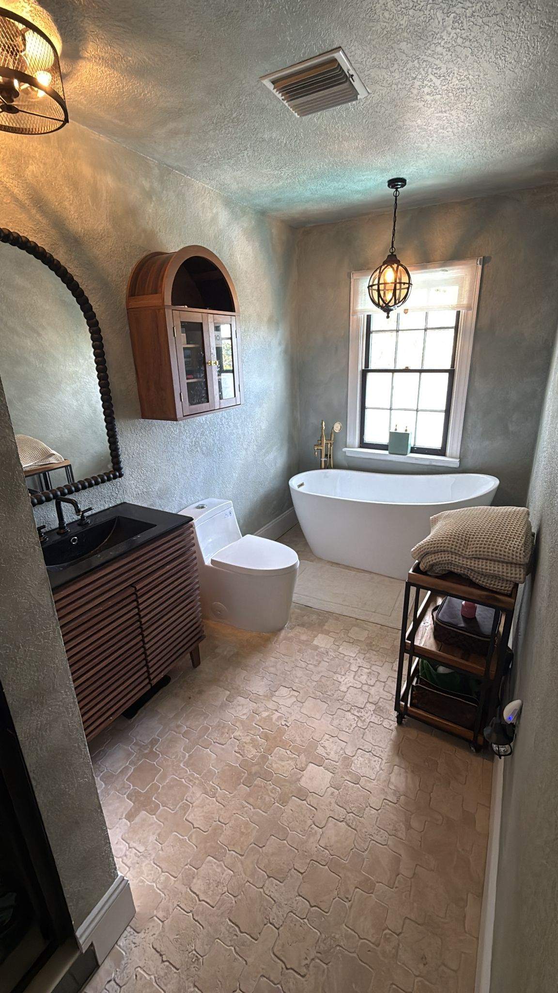 Luxury bathroom with arabesque tile floor, arched mirror, and chandelier — coastal tile installation in Siesta Key home
