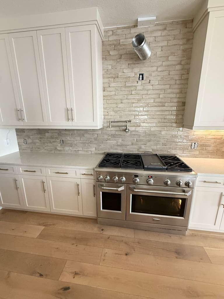 Kitchen with natural hardwood flooring and custom tile backsplash — hardwood floor installation in Sarasota home