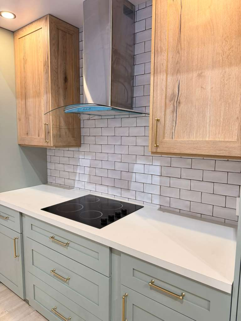 Kitchen with white subway tile backsplash and sage green lower cabinets — professional tile installation in Sarasota home