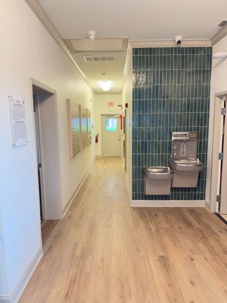 LVP wood-look flooring installed throughout hallway with teal vertical tile accent wall — luxury vinyl plank installation in Sarasota